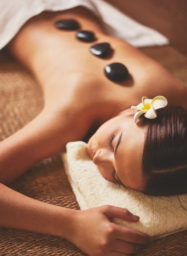 mulher recebendo massagem com pedras circulares em cima das costas